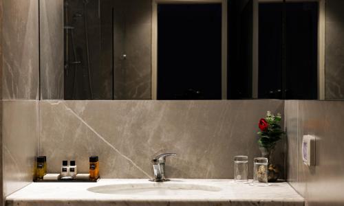 a bathroom sink with a mirror and a red rose at Lev Yerushalayim Hotel in Jerusalem