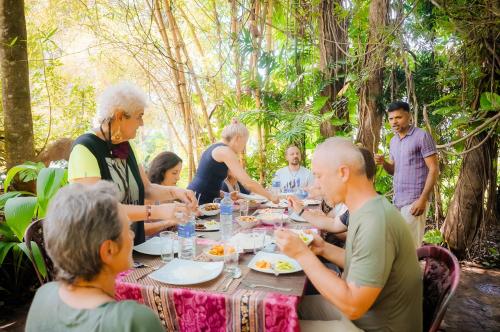 a group of people sitting around a table eating food at Leel’s Safari Cottage in Udawalawe