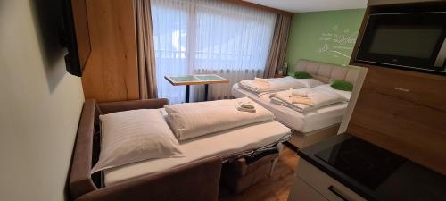 a small room with two beds and a television at Alpenhaus Donnerkogel in Annaberg im Lammertal