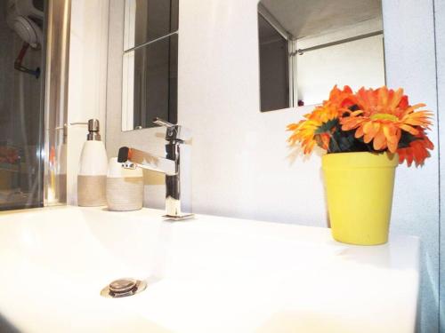 a yellow vase with flowers sitting on a bathroom sink at Le Zen in La Ciotat