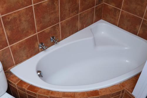 a white toilet in a bathroom with a tile wall at Thaba Legae Guest Lodge in Rustenburg