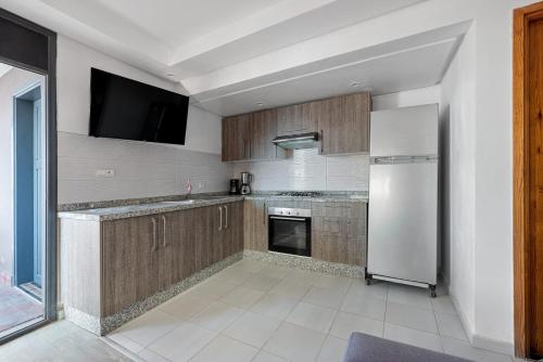 a kitchen with wooden cabinets and a white refrigerator at Imsouane Bay 2 Bedroom Suite Ocean View Terrace in Imsouane