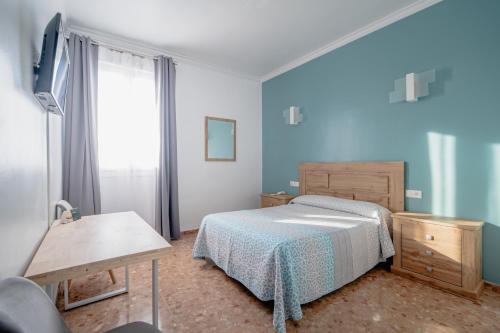 El ArahalにあるHotel Chamizoのベッドルーム1室(ベッド1台、テーブル、窓付)