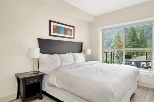a white bedroom with a bed and a window at 3BR Lakeside Dream Penthouse with Roof Deck Views in Harrison Hot Springs