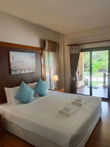 a bedroom with a large white bed with blue pillows at Chaithalay Khanom Resort in Ban Phang Phrao