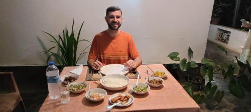 a man standing in front of a table with food at Leel’s Safari Cottage in Udawalawe