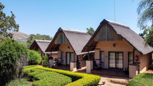 two cottages with green hedges in front of them at Thaba Legae Guest Lodge in Rustenburg