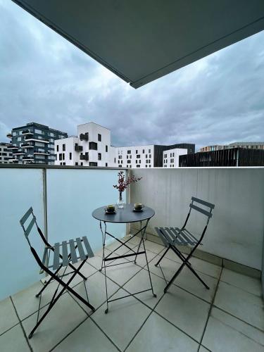 une table et des chaises sur un balcon avec vue sur une ville dans l'établissement Fillettes-Stade de France-Parking, à Aubervilliers