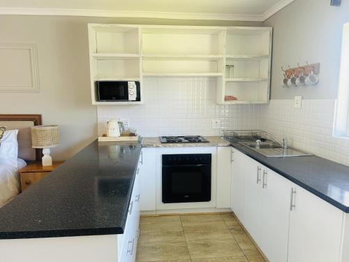 a kitchen with white cabinets and a black counter top at Tranquility Guesthouse in Kempton Park