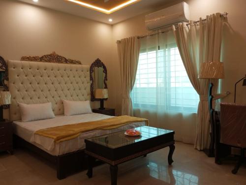 1 dormitorio con 1 cama grande y 1 mesa en Hotel Luxe Heights Lahore en Lahore