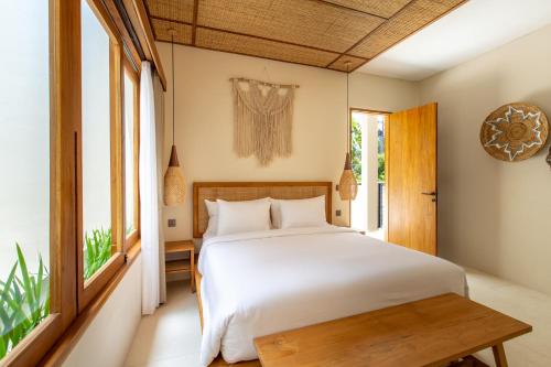 a bedroom with a white bed and a window at Bingin Sebelas in Uluwatu