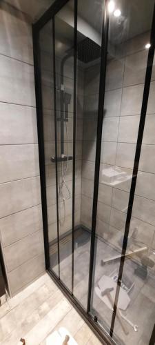 a shower with glass doors in a room at Maison de ville cosy in Kergrist