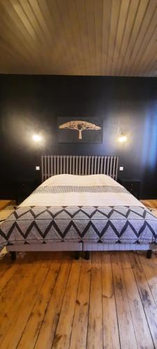 een bed in een kamer met een zwarte muur bij Maison de ville cosy in Kergrist