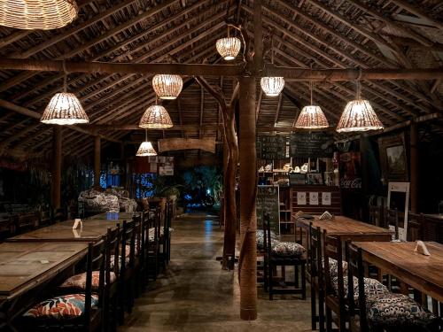a restaurant with wooden tables and chairs and chandeliers at Valampuri Kite Resort in Kalpitiya