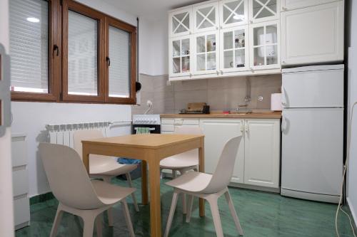 a kitchen with a wooden table and white appliances at Tommy Apartment in Belgrade