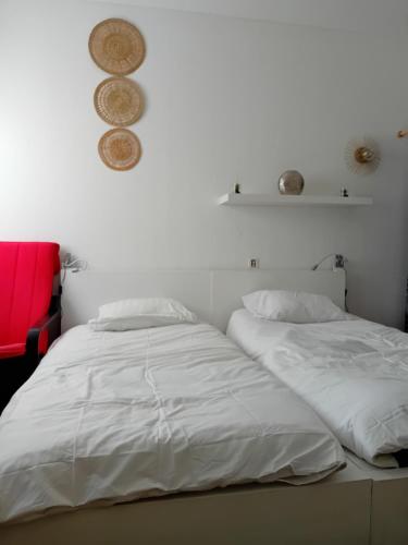a bedroom with two white beds and a red chair at Centre ville d'Amelie les bains in Amélie-les-Bains-Palalda