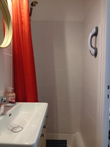 a bathroom with a sink and a red shower curtain at Centre ville d'Amelie les bains in Amélie-les-Bains-Palalda