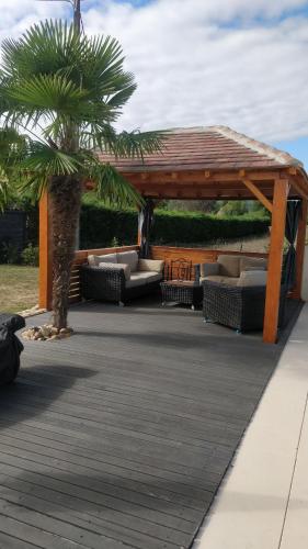 a wooden pavilion with couches and a palm tree at Le Petit Bonheur in Sergeac