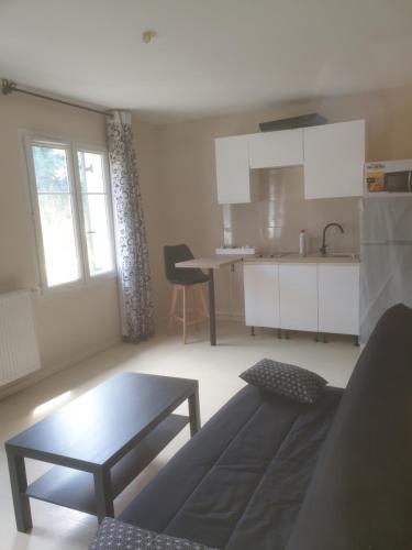 un salon avec un canapé et une table et une cuisine dans l'établissement Studio meublé proche Métro JO24, à Noisy-le-Sec
