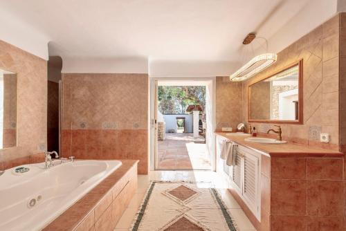 a bathroom with a tub and a sink and a mirror at Villa Sa Tanca IBIZA located PUIG D'EN VAll, 6B , Pool , Tennis in Montecristo