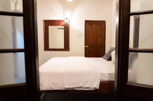een slaapkamer met een wit bed en een spiegel bij Beragala Serene Villa in Beragala