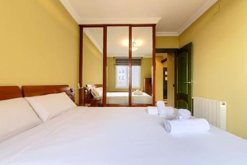 a bedroom with a large white bed and a bathroom at San Mamés Football & Parking in Bilbao