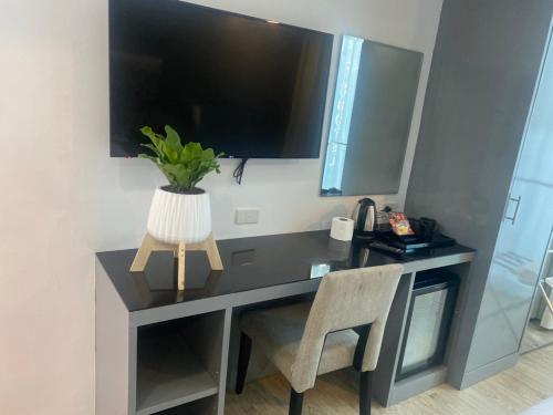 a desk with a chair and a television on a wall at 8 Hotel & cafe in Bangkok