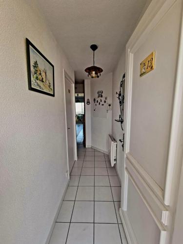 - un couloir doté de carrelage blanc et d'un lustre dans l'établissement Plage océan, à Mimizan