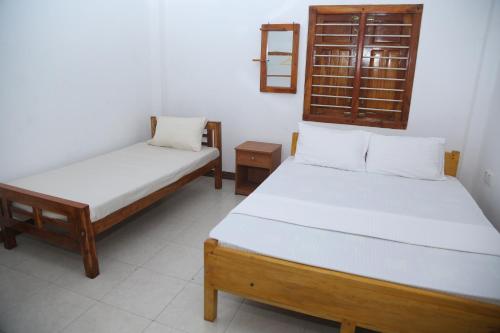 een slaapkamer met 2 bedden en een spiegel aan de muur bij Rose Fort Homestay in Jaffna