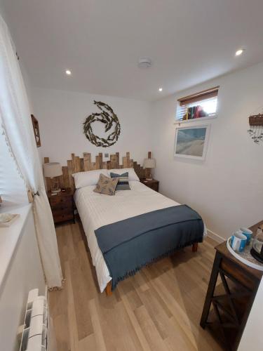 Un dormitorio con una cama grande y una ventana en Beachcroft Beach Snug, en Seaton
