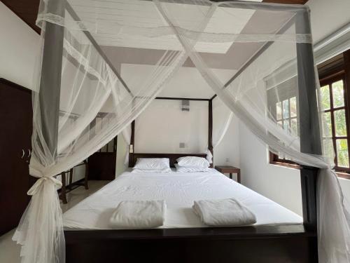 1 dormitorio con cama con dosel y cortinas blancas en Tanzanite place, en Tangalle