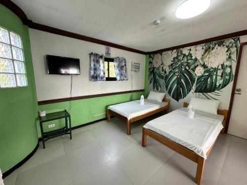 a room with two beds and a tv on the wall at Generosa Resort in Bauang