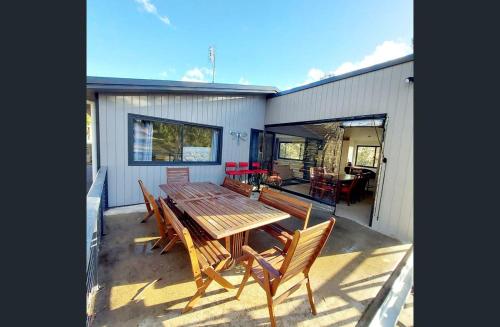 Une grande table et des chaises en bois sont disponibles sur la terrasse. dans l'établissement Huge Home, 9 Bed, 6 Bath, Sleeps 22, Central Location, Walk to Shops, à Jindabyne