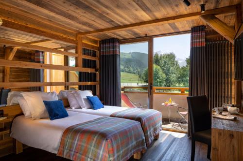 a bedroom with two beds and a balcony with a view at Hotel Cote Brune in Les Deux Alpes