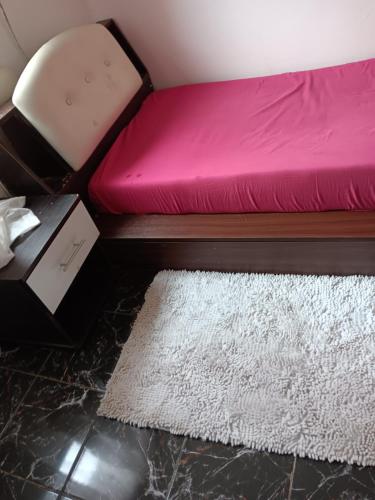a bedroom with a pink bed and a white rug at MIKEA in Antananarivo