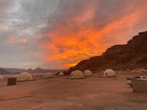 a group of domes in the desert with a sunset at Rum Aranda camp & Jeep Tour in Wadi Rum