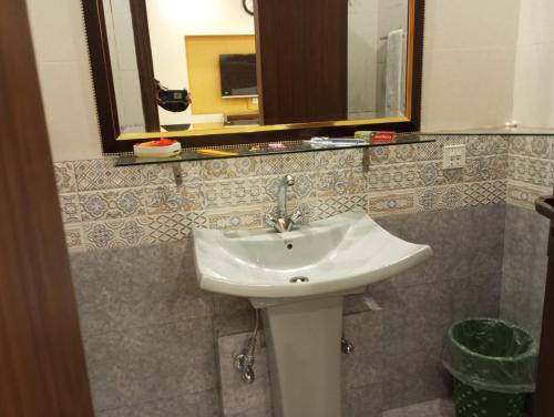a bathroom with a white sink and a mirror at Hotel Luxe Heights Lahore in Lahore