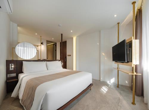 a bedroom with a large bed and a flat screen tv at Nidhra Boutique Hotel Bangkok Sukhumvit in Bangkok