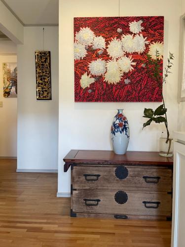 a vase on a dresser in a room with a painting at Kashiwanoha Hotspring Garden Villa&Suite Room in Kashiwa