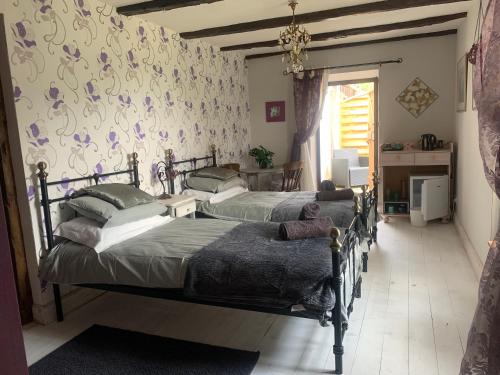 - une chambre avec 2 lits et un mur orné de fleurs dans l'établissement Sous le Chêne, à Saint-Bazile