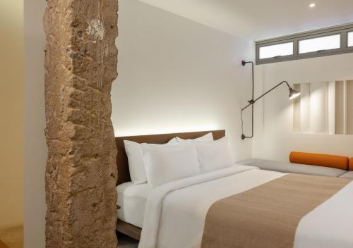 a bedroom with a white bed and a window at Nidhra Boutique Hotel Bangkok Sukhumvit in Bangkok