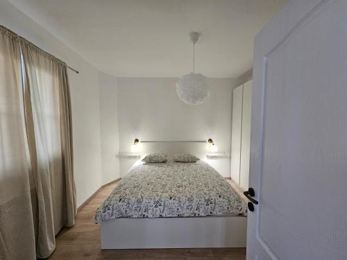 Dormitorio blanco con cama y lámpara colgante en Apartment Una, en Murter