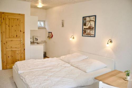 a bedroom with a white bed and a wooden table at schöner Gartenbungalow (Nr. 2) mit Terrasse - Strandvogtei Sellin in Ostseebad Sellin