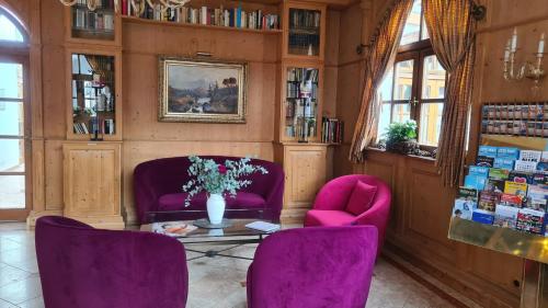 a room with two purple chairs and a table with flowers at Hotel Lechnerhof Unterföhring in Munich