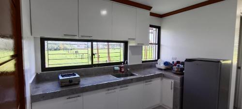 cocina con armarios blancos, fregadero y ventana en Casa Victoria Pension House-Sophia Z en Somosomo