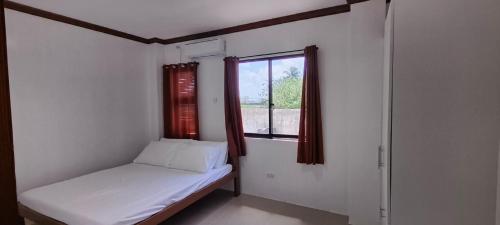 een kleine kamer met een bed en een raam bij Casa Victoria Pension House-Sophia Z in Somosomo