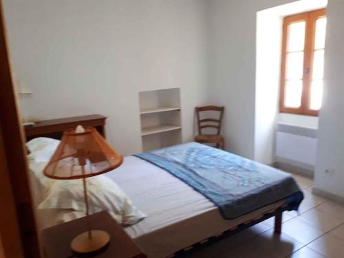 een slaapkamer met een bed met een lamp en een stoel bij Maison de village calme et agréable in Albitreccia