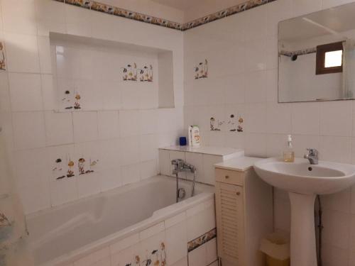 een badkamer met een wastafel, een bad en een wastafel bij Maison de village calme et agréable in Albitreccia
