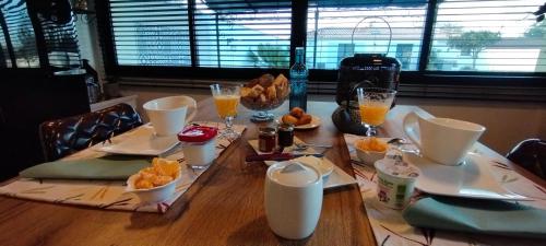 Claire & Co Chambre d'hôtes في بورنيك: طاولة مليئة بالأطباق وأكواب عصير البرتقال