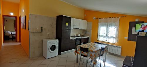 a kitchen with a washing machine and a table with chairs at Complesso turistico Aurora - Appartamenti in Poggio Picenze